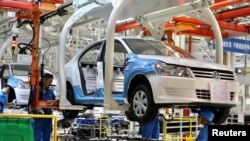 Nhân viên làm việc lắp ráp xe tại một nhà máy của SAIC Volkswagen ở Urumqi, Khu tự trị Duy Ngô Nhĩ Tân Cương, Trung Quốc.