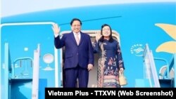 Thủ tướng Việt Nam Phạm Minh Chính (trái) cùng phu nhân vẫy tay chào trước khi lên máy bay rời sân bay Nội Bài ở Hà Nội hôm 28/11 để tham dự COP28, dự kiến khai mạc ở Dubai hôm 30/11.