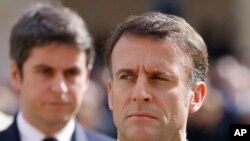 FILE - French President Emmanuel Macron and French Prime Minister Gabriel Attal, background, attend a ceremony in Paris, March 20, 2024. Following a snap legislative election, Macron has lost his parliamentary majority.