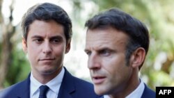 FILE - French Education and Youth Minister Gabriel Attal (L) looks at France's President Emmanuel Macron addressing the audience at a vocational school in Orange, Southeastern France, Sept. 1, 2023. 