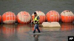 Yon travaye enspekte barye flotant Texas ap sevi kom barye pou anpeche migran yo travese rivye Rio Grande a, 21 Out, 2023. 