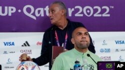 Jwe Brezilyen Dani Alves (devan) ak antrene seleksyon Brezilyen an Tite pandan yon konferans pou lapres nan Doha, Qatar, 1 Dec. 2022. 