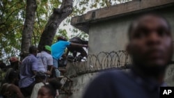 Journalists climb up a wall to take cover from gunfire, after being shot at by armed gangs at the General Hospital in Port-au-Prince, Haiti, Dec. 24, 2024.