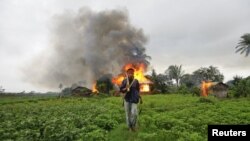 Người sắc tộc Rakhine mang theo vũ khí tự chế phía trước căn nhà đã bị đốt cháy trong vụ bạo động sắc tộc giữa người Rakhine Phật giáo và cộng đồng Hồi giáo Rohingya ở Sittwe, Miến Ðiện