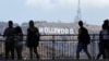 Tourists walk past the Hollywood sign as they visit a shopping complex along Hollywood