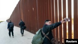 Migrants camp at the border wall on the U.S. side