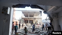 Palestinians inspect damage at the site of an Israeli strike in the central Gaza Strip