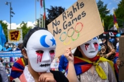 Tibetan and Uyghur activists hold placards and wear masks during a protest against Beijing 2022