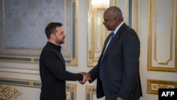 This handout photograph taken and released by the Ukrainian Presidential Press Service on October 21, 2024 shows Ukrainian President Volodymyr Zelensky (L) and US Secretary of Defense Lloyd Austin shaking hands during their meeting in Kyiv.