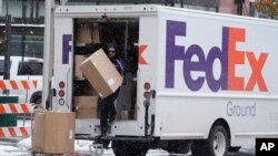 Foto Achiv: Yon anplwaye FedEx pote yon koli, 17 Nov. 2022. 