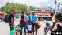 Haitian migrants who have just arrived after U.S. authorities flew them out of a Texas border city on Sunday hire moto taxis after leaving the airport, in Port-au-Prince, Sept. 19, 2021.