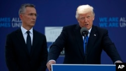 TTK NATO Jens Stoltenberg lắng nghe bài diễn văn của ông Trump trong lễ khai trương khu triển lãm các chứng tích lịch sử từ Trung tâm Thương Mại Thế giới và Bức Tường Berlin cho trụ sở mới của NATO ở Brussels, ngày 25/5/2017. (AP Photo/Evan Vucci) 