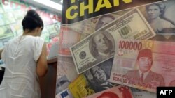 Tư liệu: Đồng đôla Mỹ,đồng rupiah của Indonesia và đồng nhân dân tệ của Trung Quốc trên một tấm quảng cáo tại một địa điểm đổi tiền ở Jakarta. 