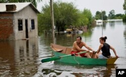 Một cặp vợ chồng chèo thuyền qua đường phố bị ngập lụt Durazno, Uruguay.