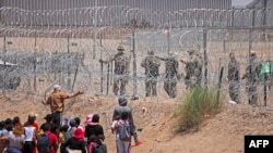 Migrants seeking to enter the United States through a barbed wire fence installed along the Rio Grande are driven away with pepper spray shots by Texas National Guard agents at the border with Ciudad Juarez, Chihuahua State, Mexico, on May 13, 2024. (Phot