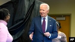 President Joe Biden, right, holding an "I Voted Early" sticker, reaches to shake the hand of a poll worker upon exiting the voting booth after casting his early-voting ballot for the 2024 general elections, in New Castle, Delaware, Oct. 28, 2024. 