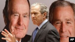 Cựu Tổng thống George W. Bush đi ngang qua một bức chân dung của chính mình và cha của ông, cựu Tổng thống George H.W. Bush.