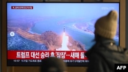 People watch a television screen showing a news broadcast with file footage of a North Korean missile test, at a train station in Seoul on January 14, 2025.