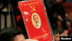 A delegate of Vietnam's Communist Party raises his membership card to vote on new policies at the closing ceremony of the 11th National Congress of the Party in Hanoi January 19, 2011