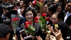 Cựu Thủ Tướng Thái Lan Yingluck Shinawatra, ở giữa, nhận hoa của các ủng hộ viên tại Tòa án Tối cao ở Bangkok sau phiên tòa xét xử bà về tội sao nhãng nhiệm vụ. Ảnh chụp ngày 1/8/2017. (AP Photo/Sakchai Lalit)