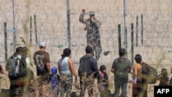 TOPSHOT - Migrant people seeking asylum in the US speak with a Texas National Guard agent after crossing the Rio Grande River in Ciudad Juarez, Chihuahua state, Mexico on March 13, 2024. (Photo by Herika Martinez / AFP)