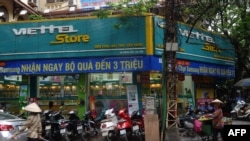 Một người bán hàng rong đi ngang một cửa hàng Viettel ở Hà Nội.