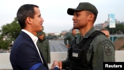 Lãnh đạo phe đối lập Venezuela Juan Guaido, người được nhiều quốc gia công nhận là lãnh đạo lâm thời hợp pháp của đất nước, bắt tay với một giới chức quân sự gần căn cứ không quân Generalisimo Francisco de Miranda "La Carlota", ở Venezuela, ngày 30/4/019. 